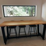 Détail du piètement trapézoïdal en acier noir et des roulettes de la table AIX.