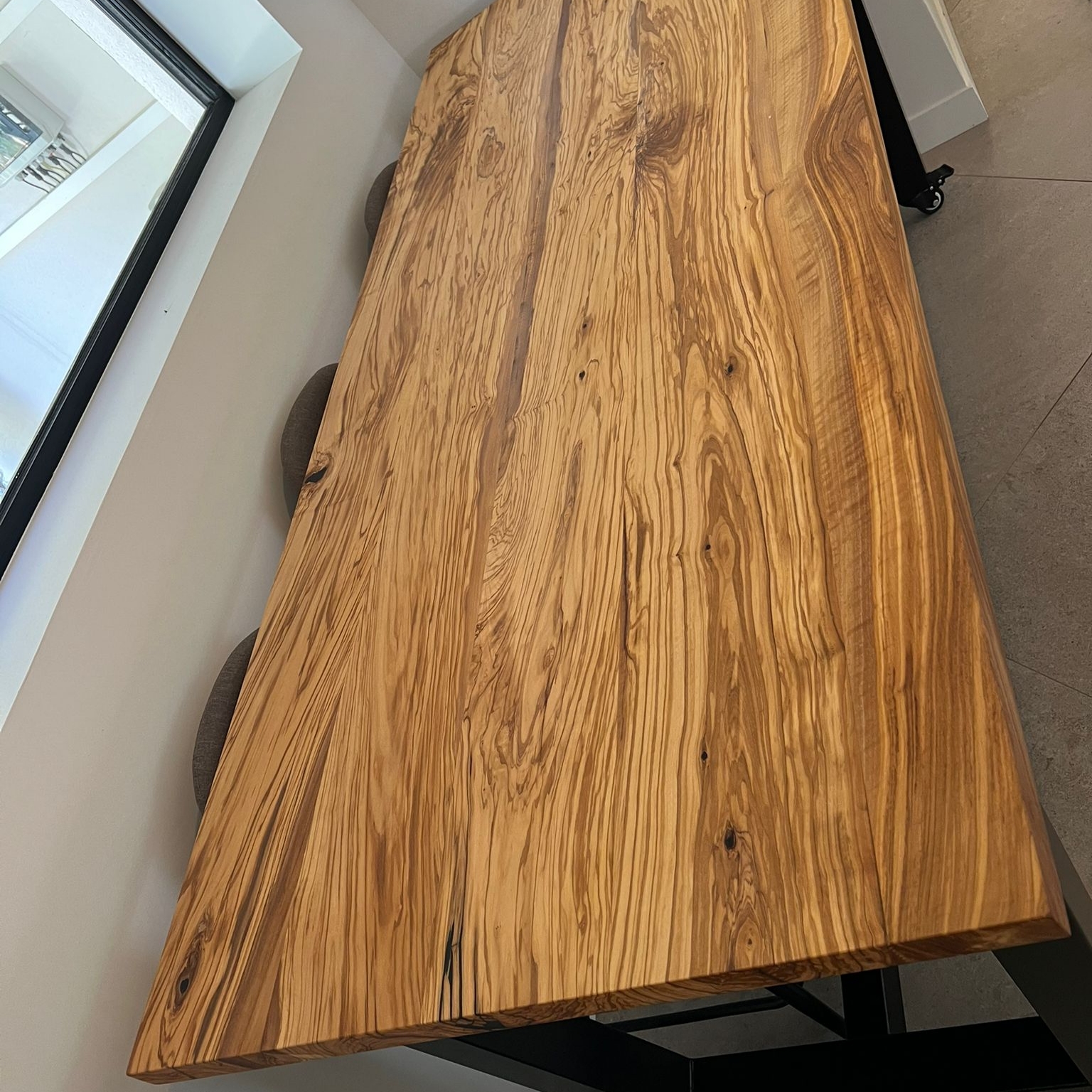 Gros plan sur les veines et le grain spectaculaires du plateau en olivier massif de la table AIX.