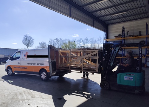 Chargement sécurisé d'une table en bois massif sur mesure dans le fourgon d'un transporteur privé pour une livraison directe sans étape.