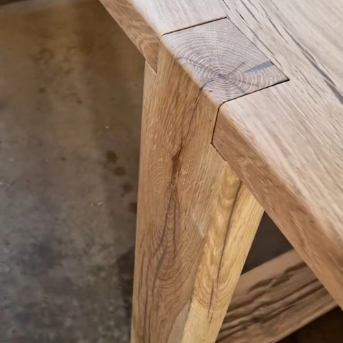 Gros plan sur un nœud naturel et le veinage du bois de chêne massif sur le plateau d'une table d'ébénisterie de luxe.
