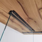 Zoom sur le système de fixation professionnel en acier reliant le plateau en chêne massif et le pied en verre de la table MENTON.